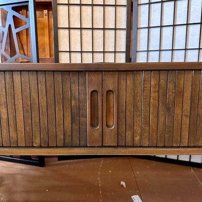 Wooden cabinet with a handle in front of a glass-paneled wall.