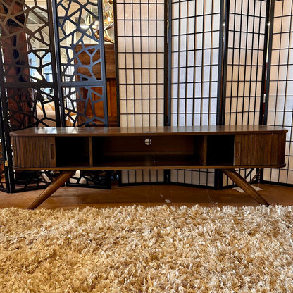 Wooden TV stand in a room with decorative screens and a textured rug.