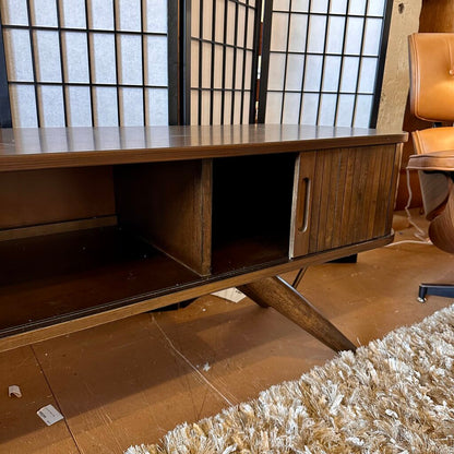 Wooden TV stand in a room with a chair and window