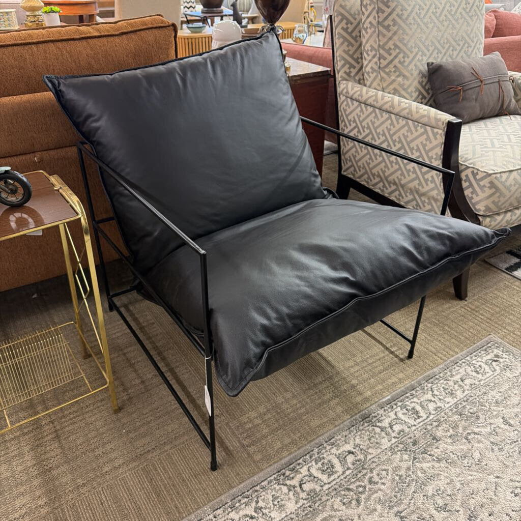 Black chair with a cushion in a room with furniture and decor