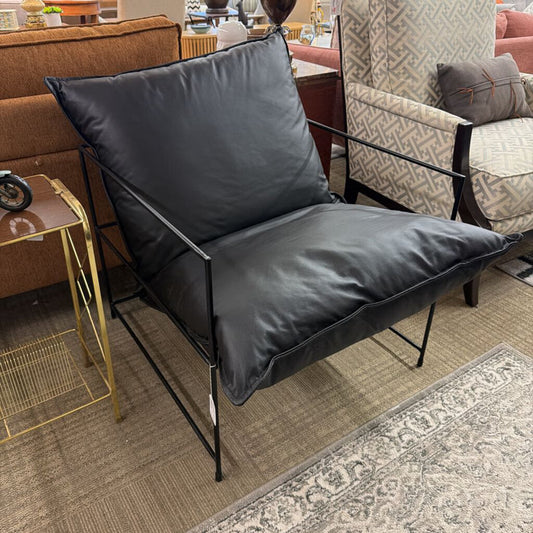 Black chair with a cushion in a room with furniture and decor