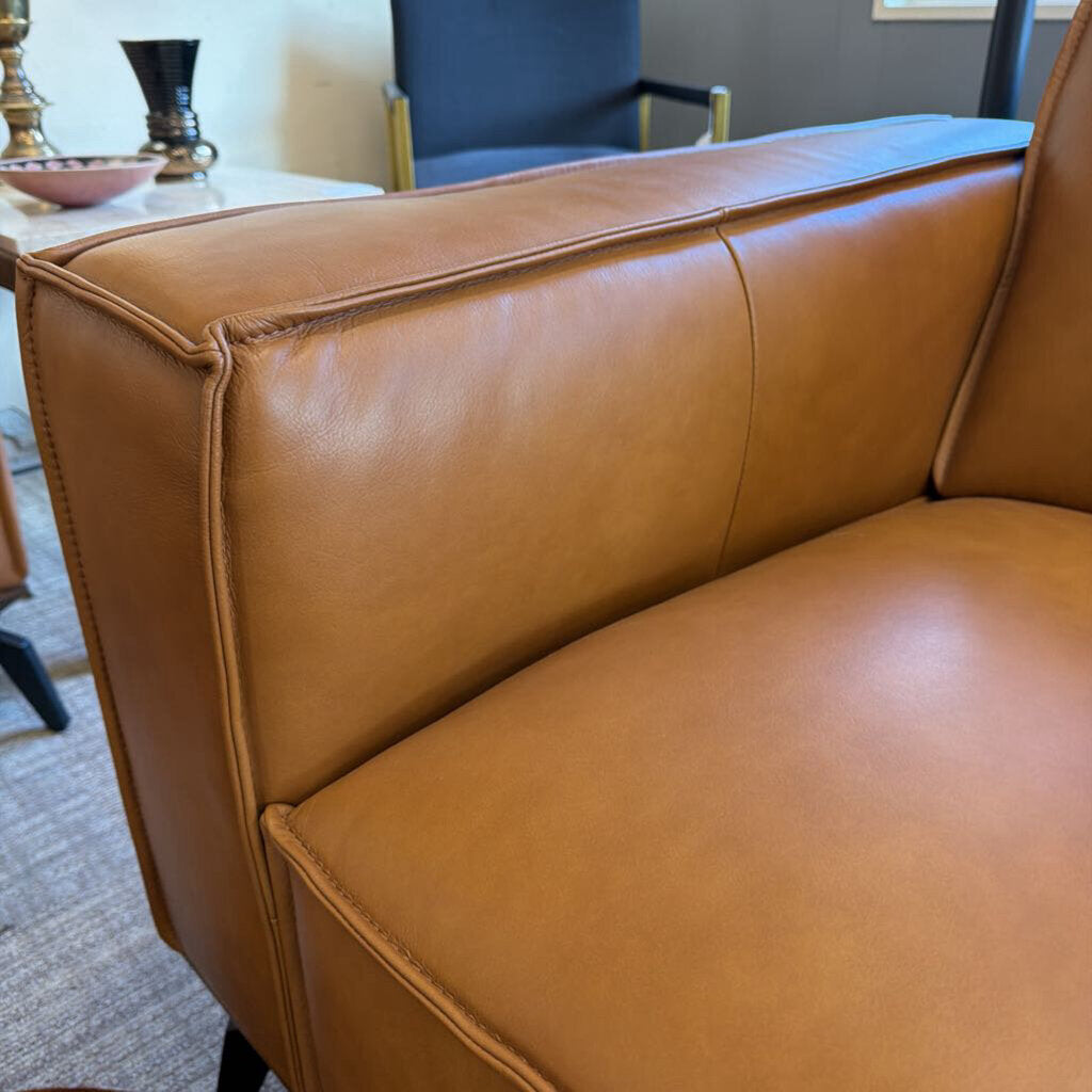 Brown leather sofa in a room with a table and chairs.