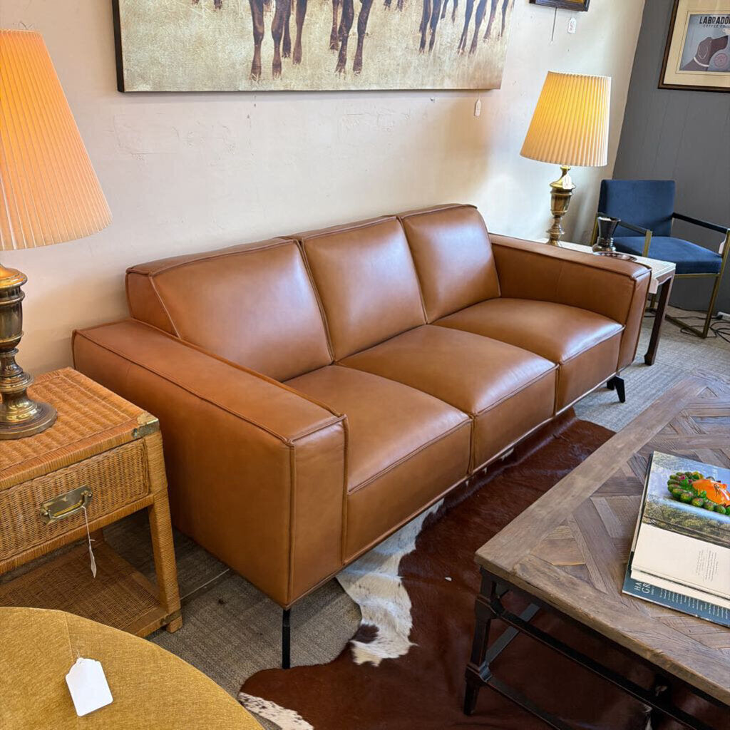 Brown leather sofa in a living room setting with lamps and a coffee table.