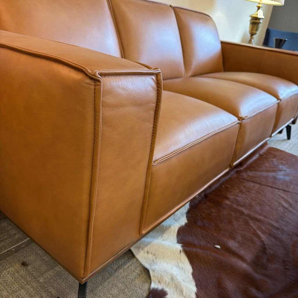 Brown leather sofa in a room with a patterned rug.