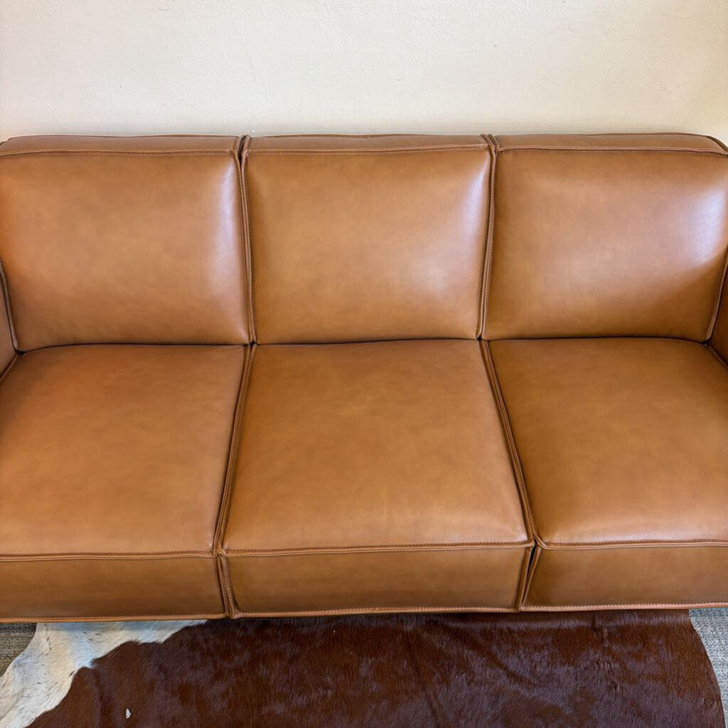 Brown leather sofa against a beige wall