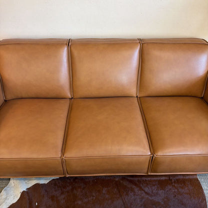 Brown leather sofa against a beige wall