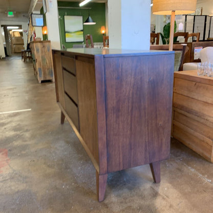 Wooden sideboard in a store setting with other furniture items.