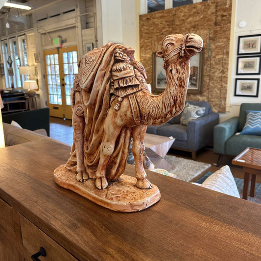 Camel statue on a wooden surface with a living room in the background