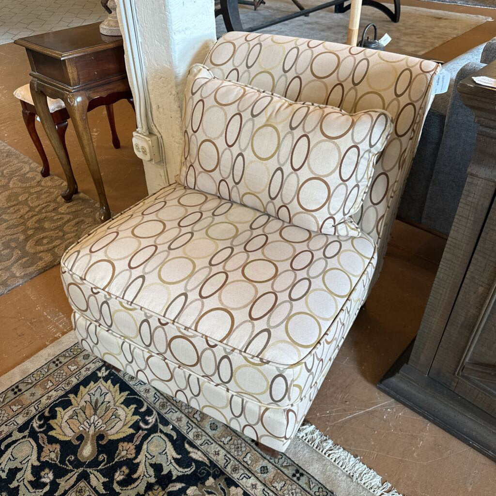 Patterned armchair in a room with a rug and wooden furniture.