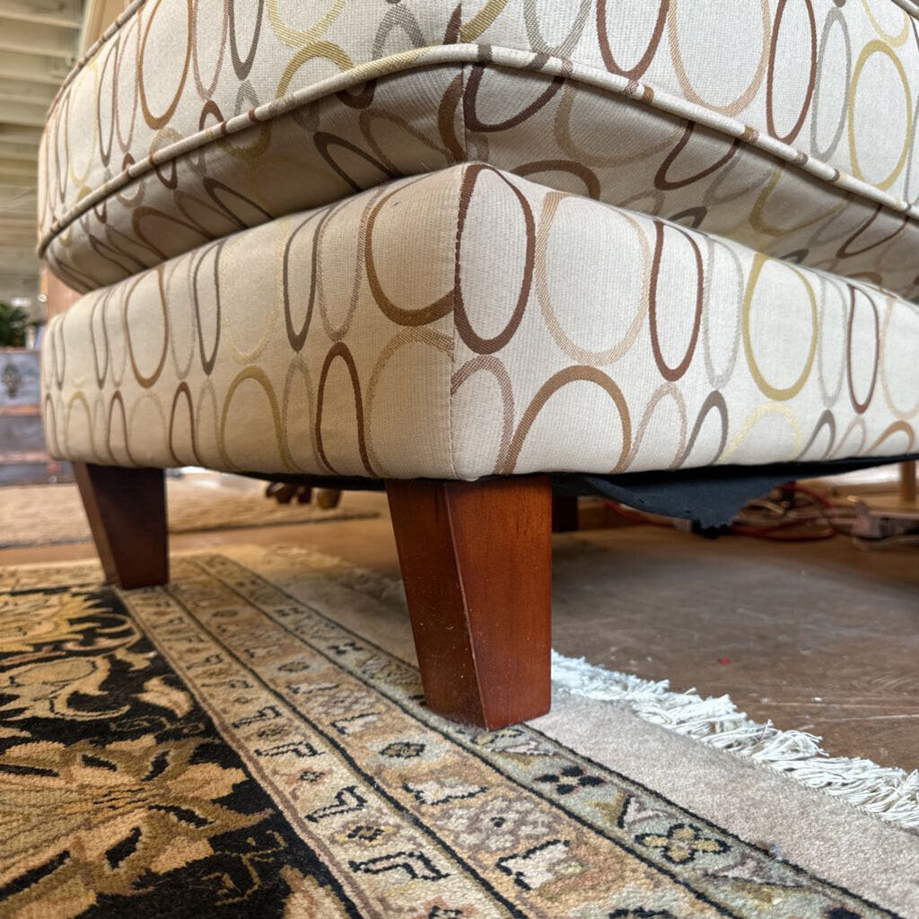 Patterned ottoman with wooden legs on a rug