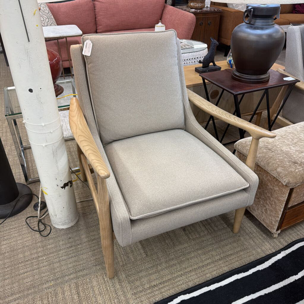 Gray armchair with wooden arms and legs in a room with furniture and decor.