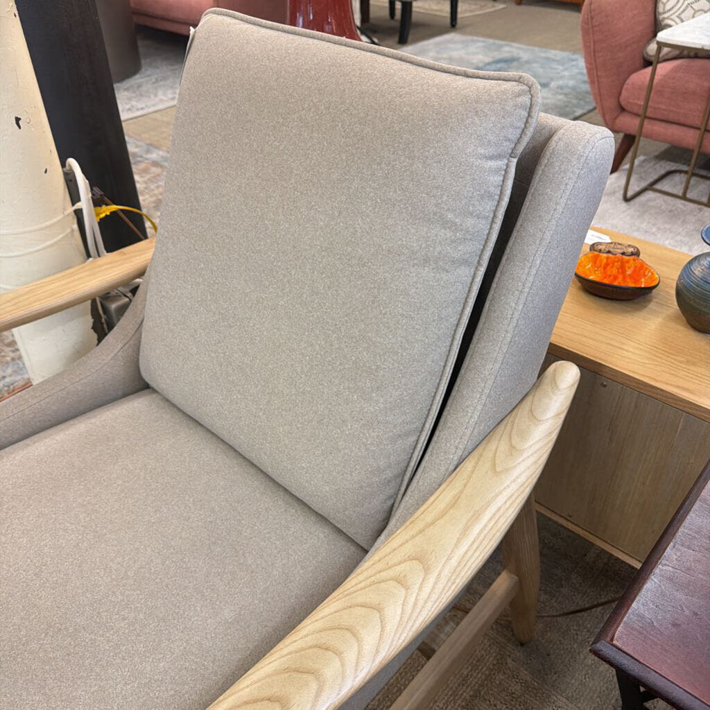 Gray upholstered chair with wooden armrests in a room setting.