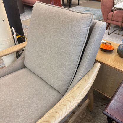 Gray upholstered chair with wooden armrests in a room setting.