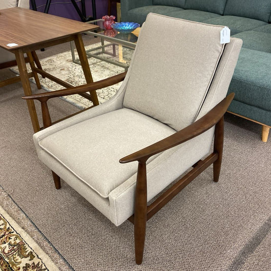 Beige armchair with wooden arms and legs in a room setting.