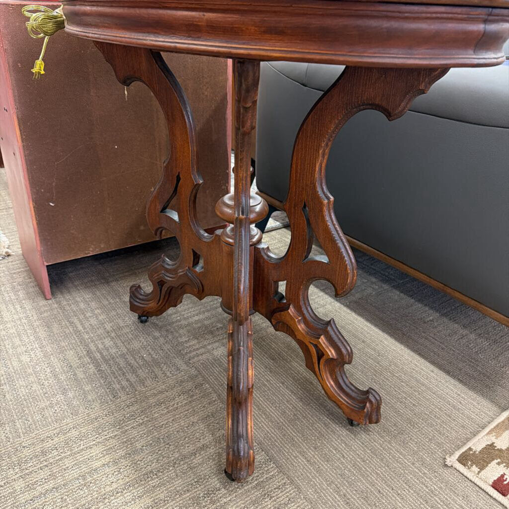 Wooden side table with intricate legs on a carpeted floor