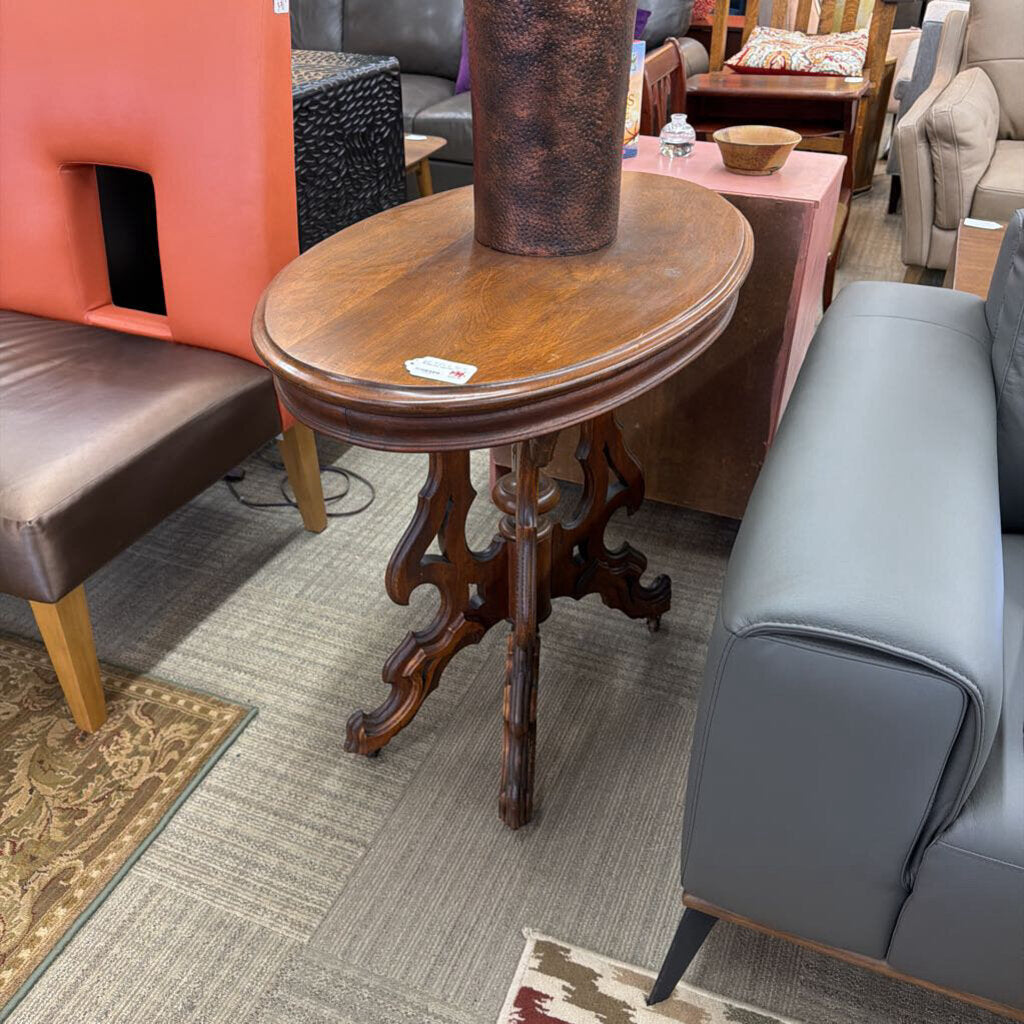 Wooden side table in a furniture store setting with various chairs and a rug.