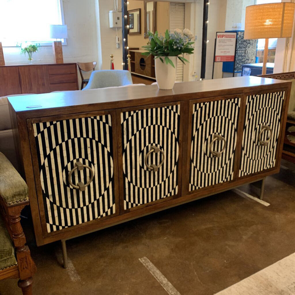 Wooden sideboard with black and white patterned doors in a showroom setting