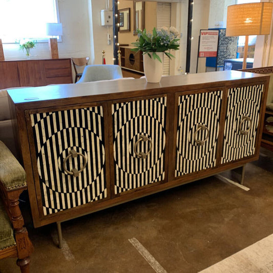 Wooden sideboard with black and white patterned doors in a showroom setting