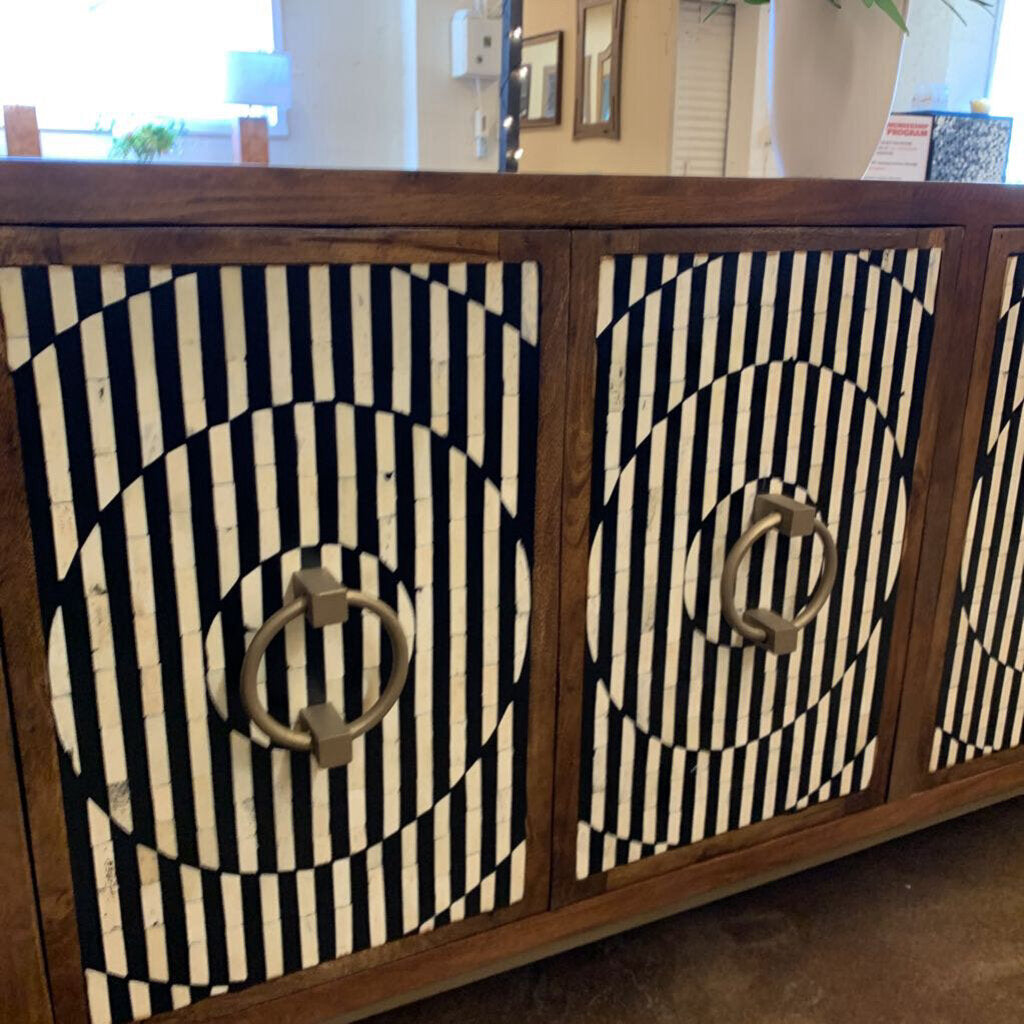 Wooden cabinet with black and white patterned doors and gold handles.