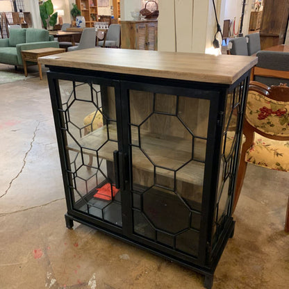 Furniture store setting with a decorative cabinet featuring glass doors.