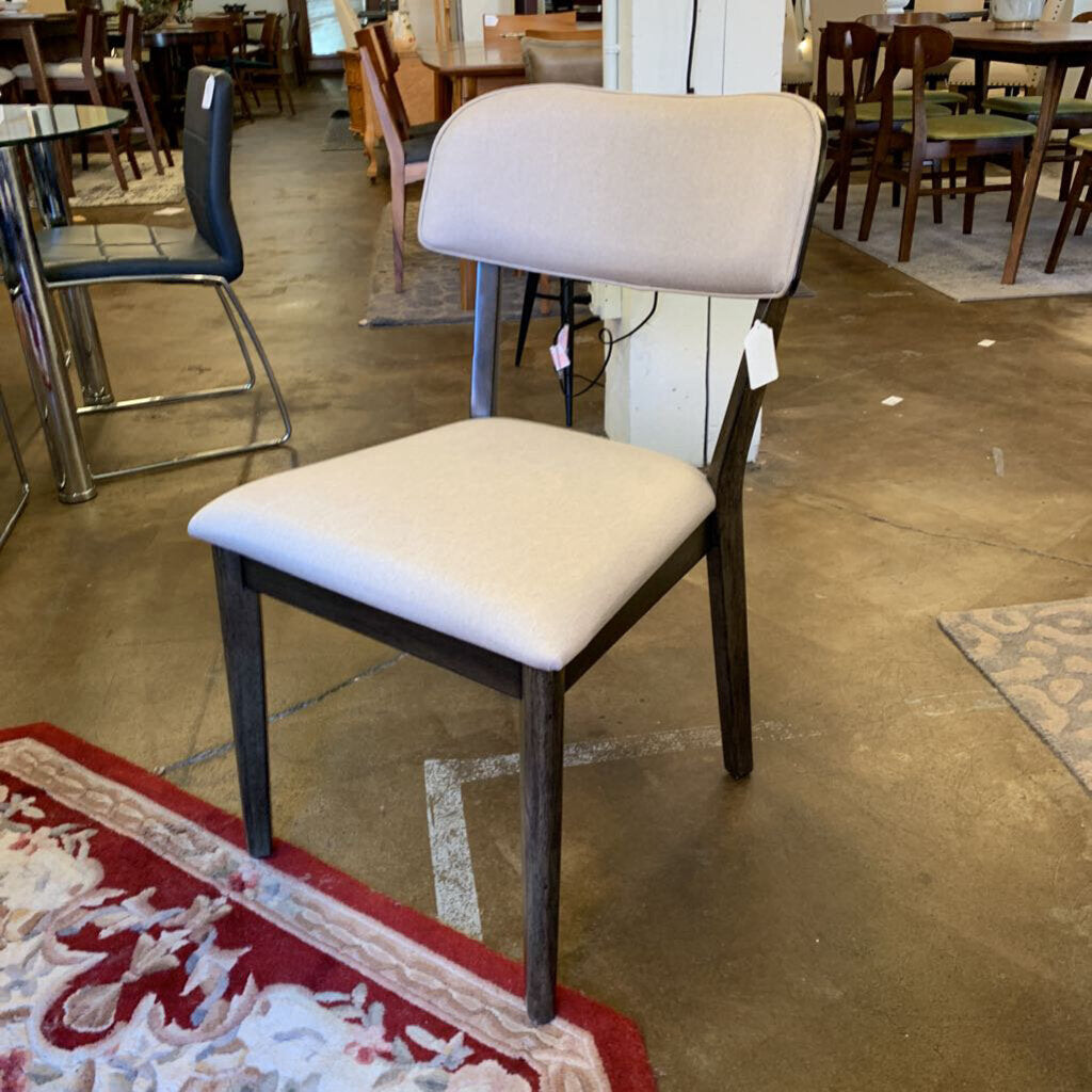 Chair with beige cushioned seat and backrest in a store setting with tables and chairs.