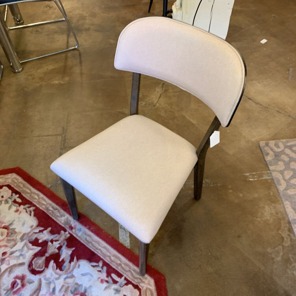 Beige chair on a concrete floor with a red and white patterned rug.