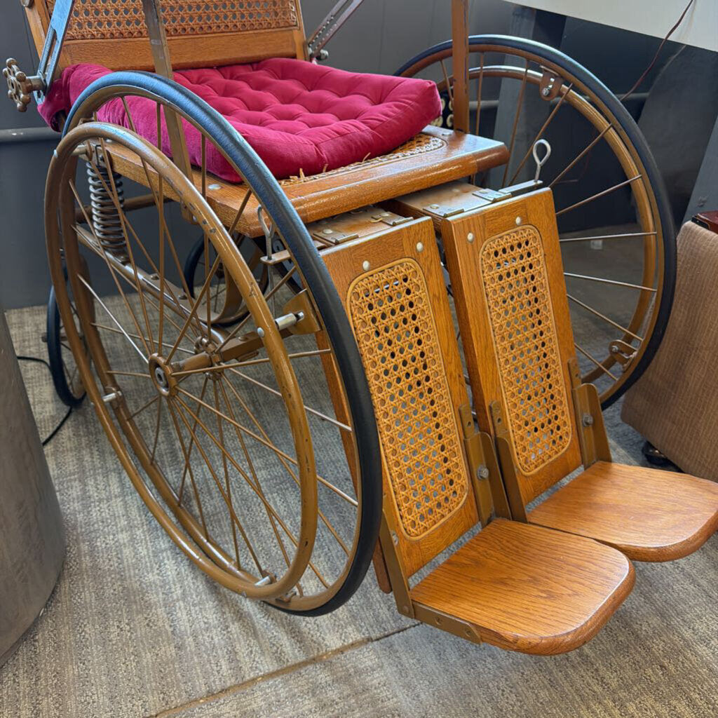 Vintage wheelchair with wooden frame and wicker backrest on a carpeted floor.