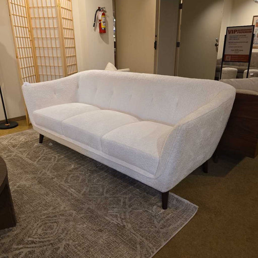 White sofa in a room with a patterned rug and wooden screen.