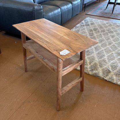 Wooden side table in a room with a blue sofa and patterned rug.
