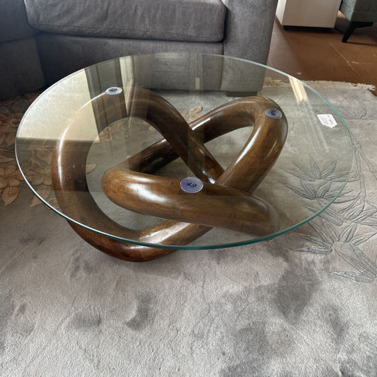 Glass coffee table with a wooden knot design in a living room setting