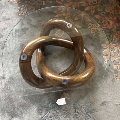 Wooden knot sculpture on a glass table with floral-patterned rug
