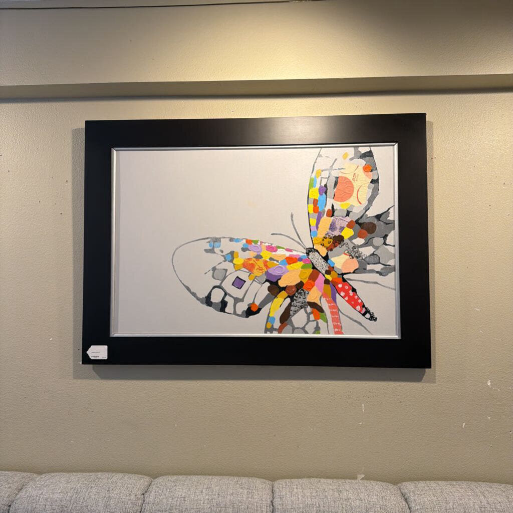 Framed colorful butterfly artwork on a wall above a sofa.