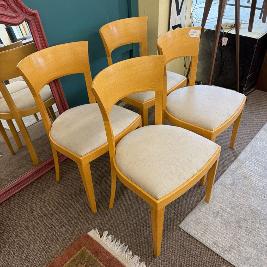 Set of wooden chairs with beige cushioned seats in a room setting.