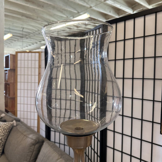 Clear glass lantern on a stand against a tiled wall