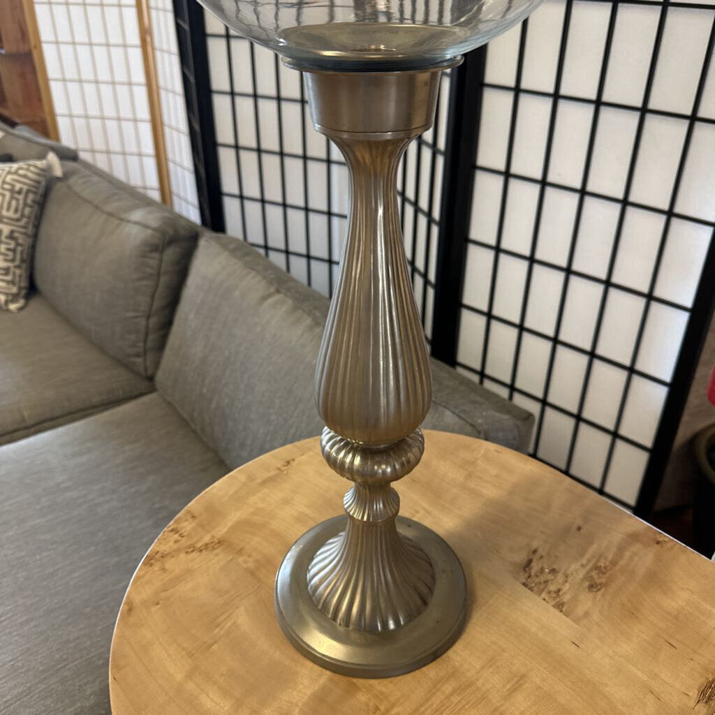 Decorative candle holder on a wooden table with a couch and screen in the background