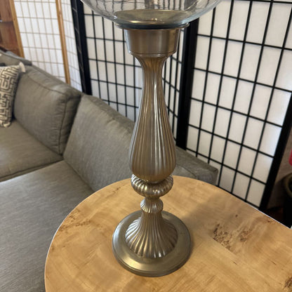 Decorative candle holder on a wooden table with a couch and screen in the background