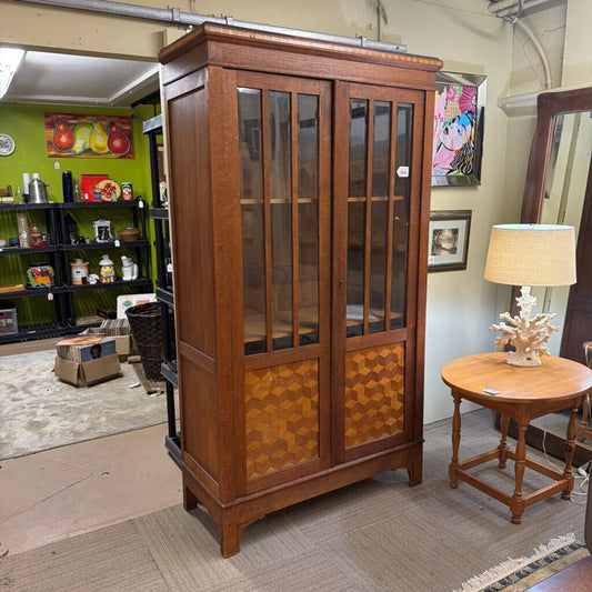 Wooden display cabinet in a room with a lamp and shelves.