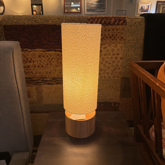 Textured table lamp on a dark surface with a patterned wall in the background