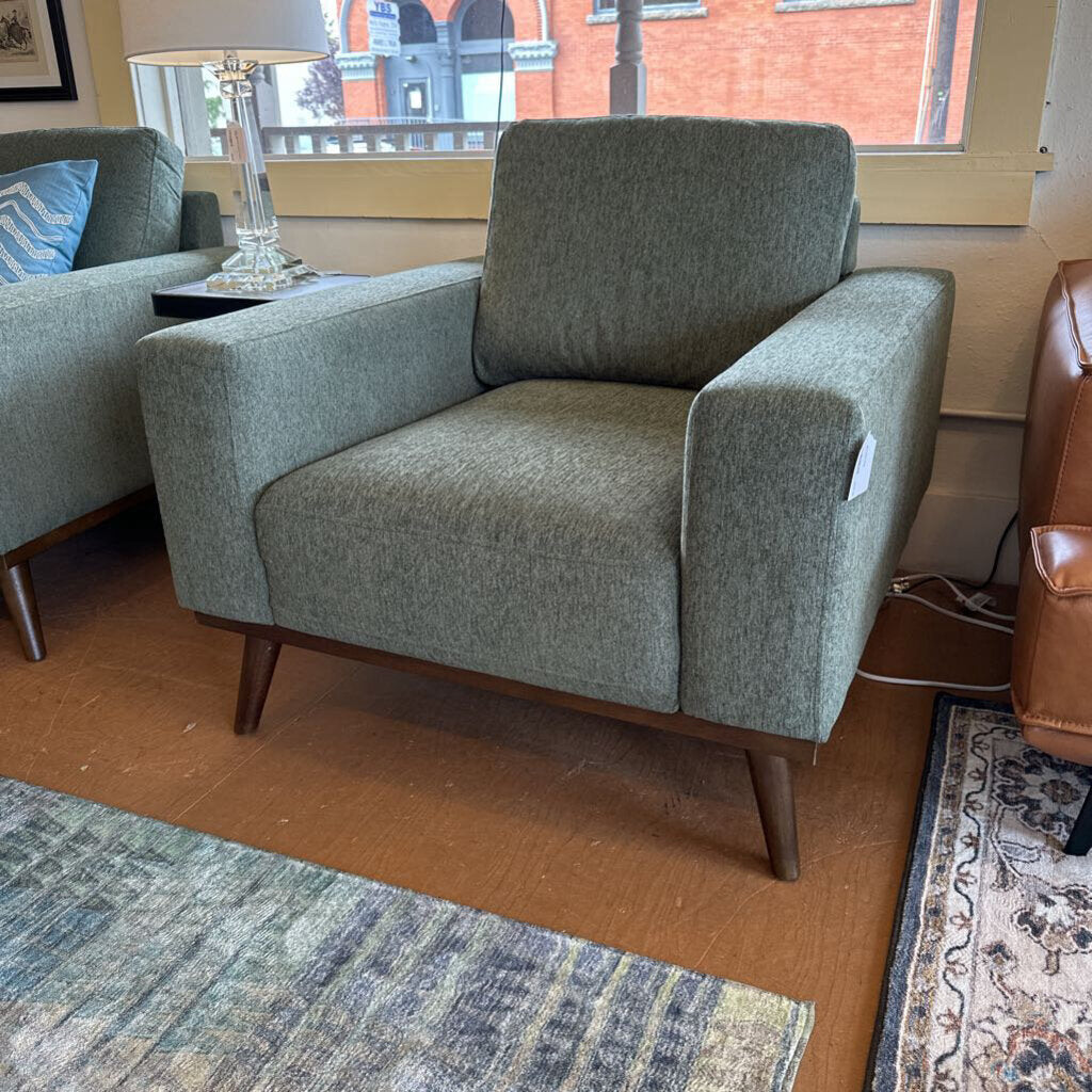 Green armchair in a room with a lamp and window