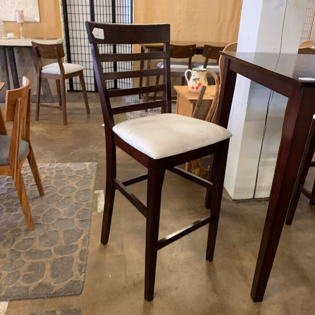 Wooden bar chair with a white cushion in a showroom setting