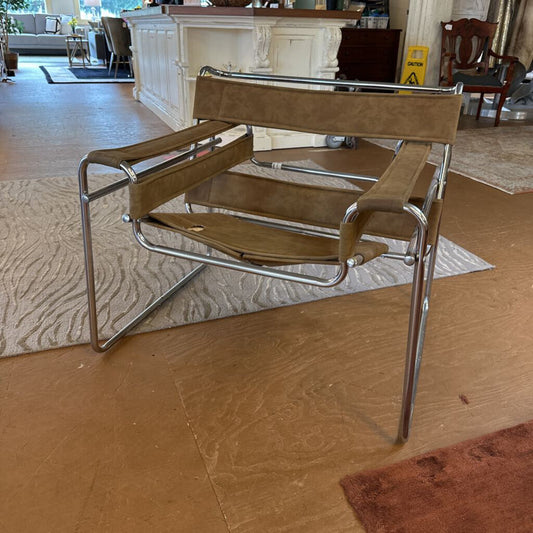 Brown chair with metal frame on a wooden floor in a room with furniture and decor.