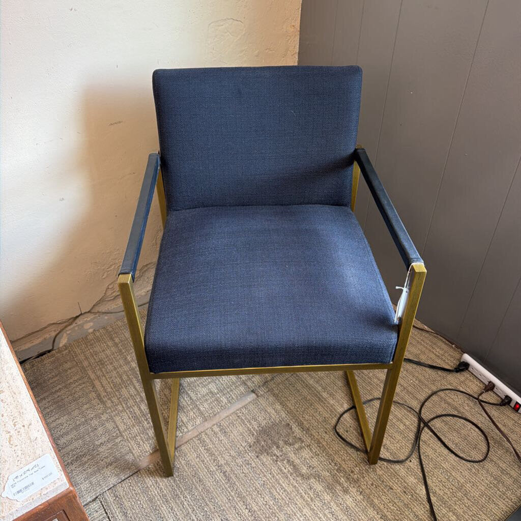 Blue chair with gold frame on a carpeted floor against a wall.