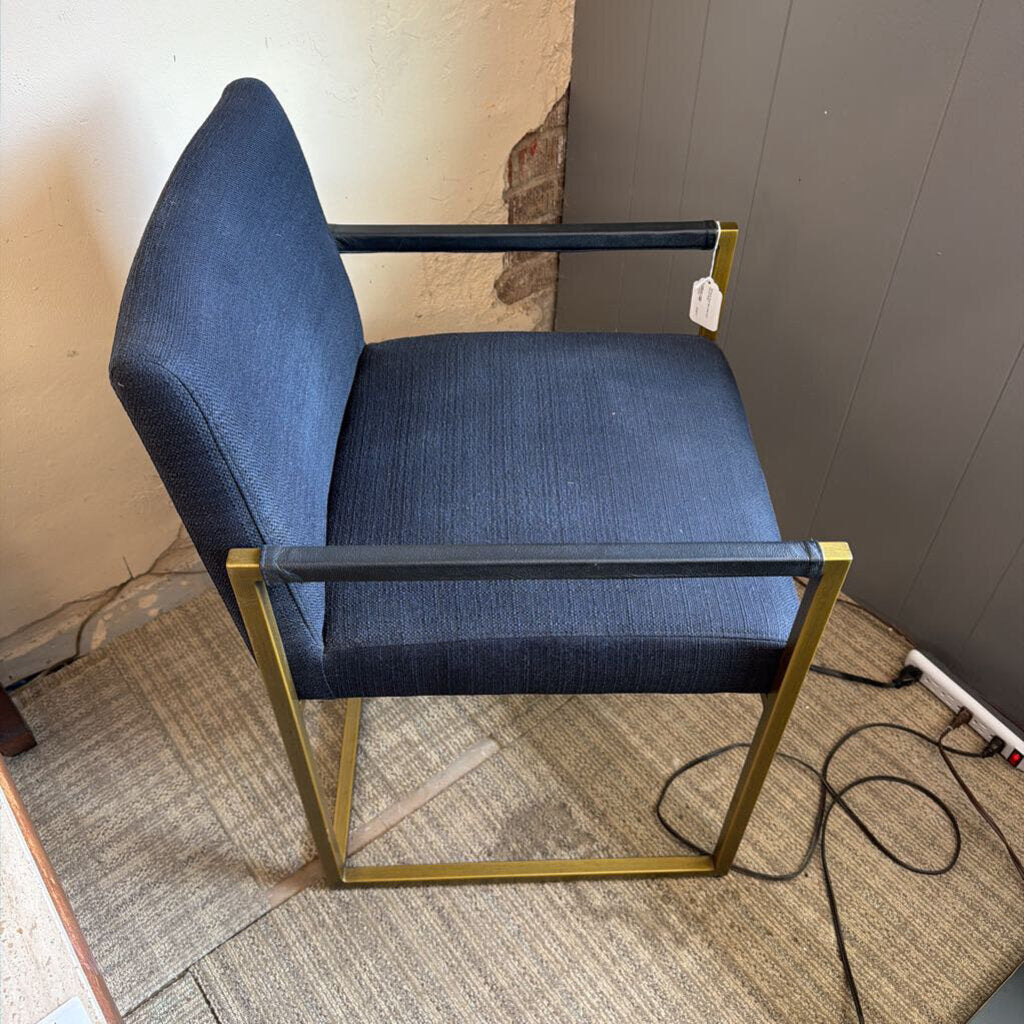 Blue chair with gold frame on a carpeted floor against a wall.
