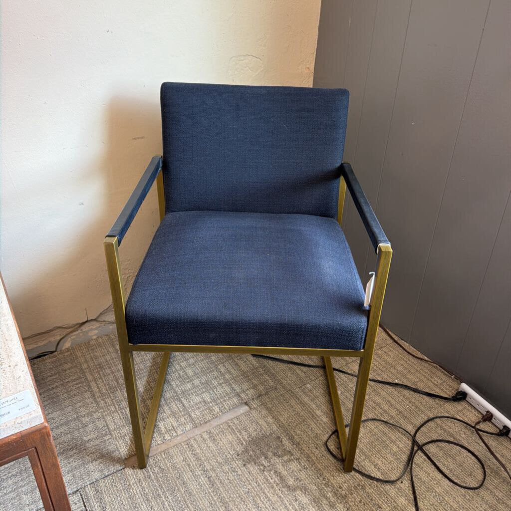Blue chair with gold frame on a carpeted floor against a wall.