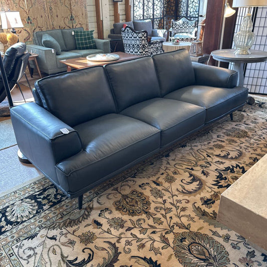 Blue leather sofa in a living room setting with patterned rug and furniture.