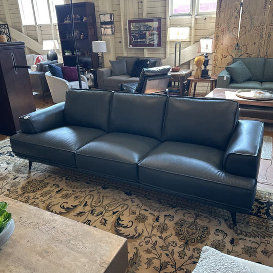 Blue leather sofa in a living room setting with other furniture and decor.