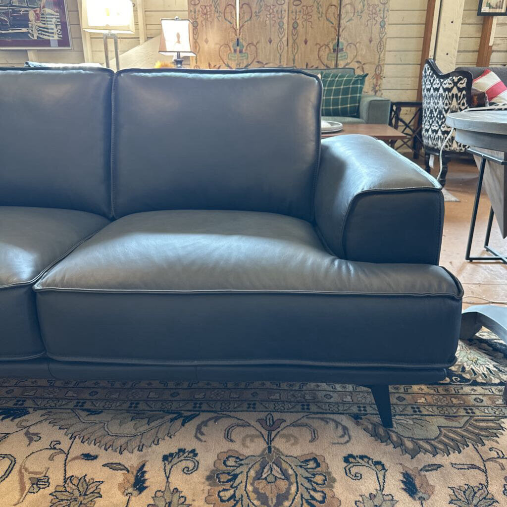 Blue leather sofa in a living room setting with a patterned rug and furniture.