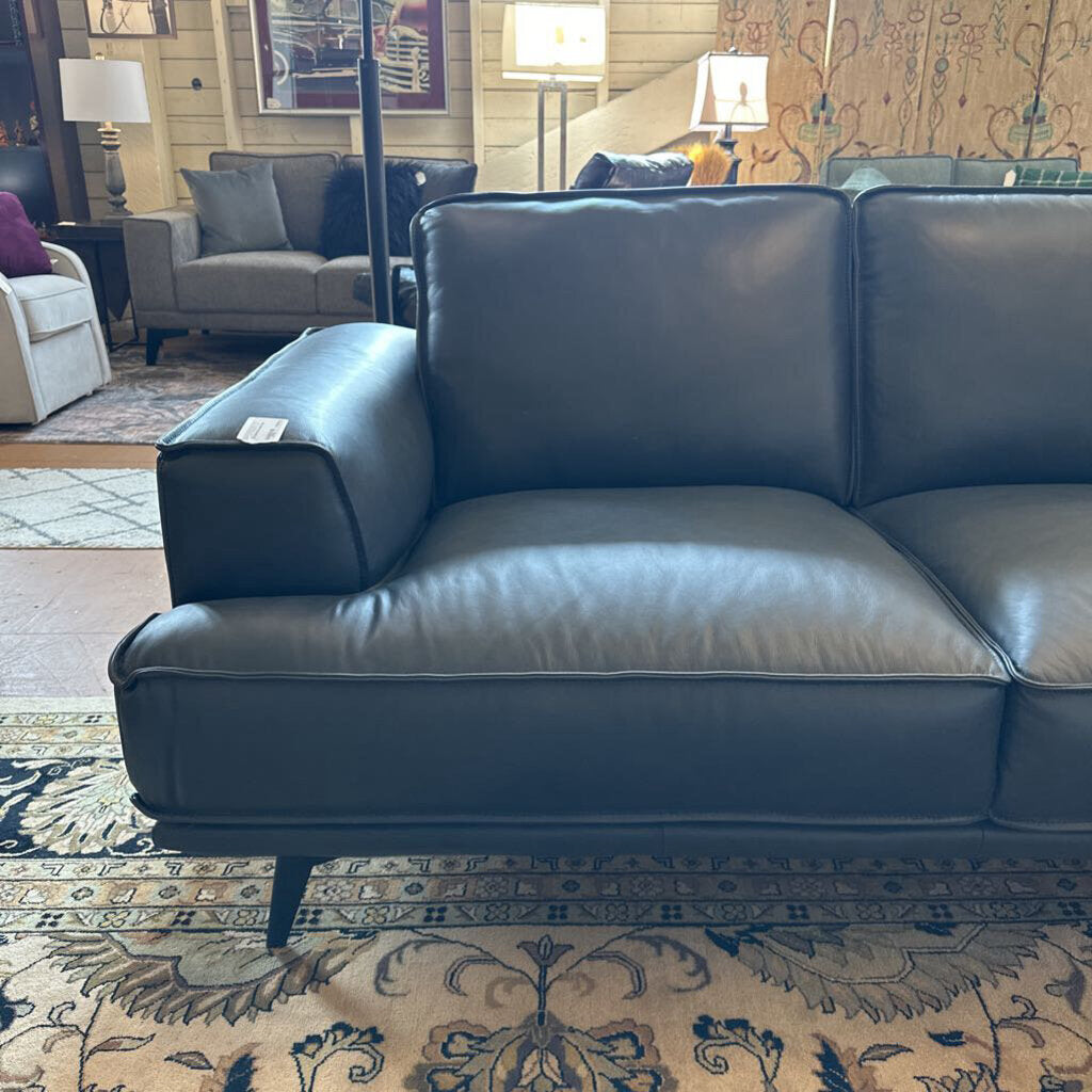 Blue leather sofa in a living room setting with other furniture and decor.