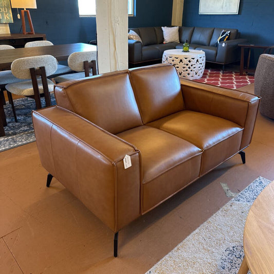 Brown leather sofa in a room with dining table and chairs