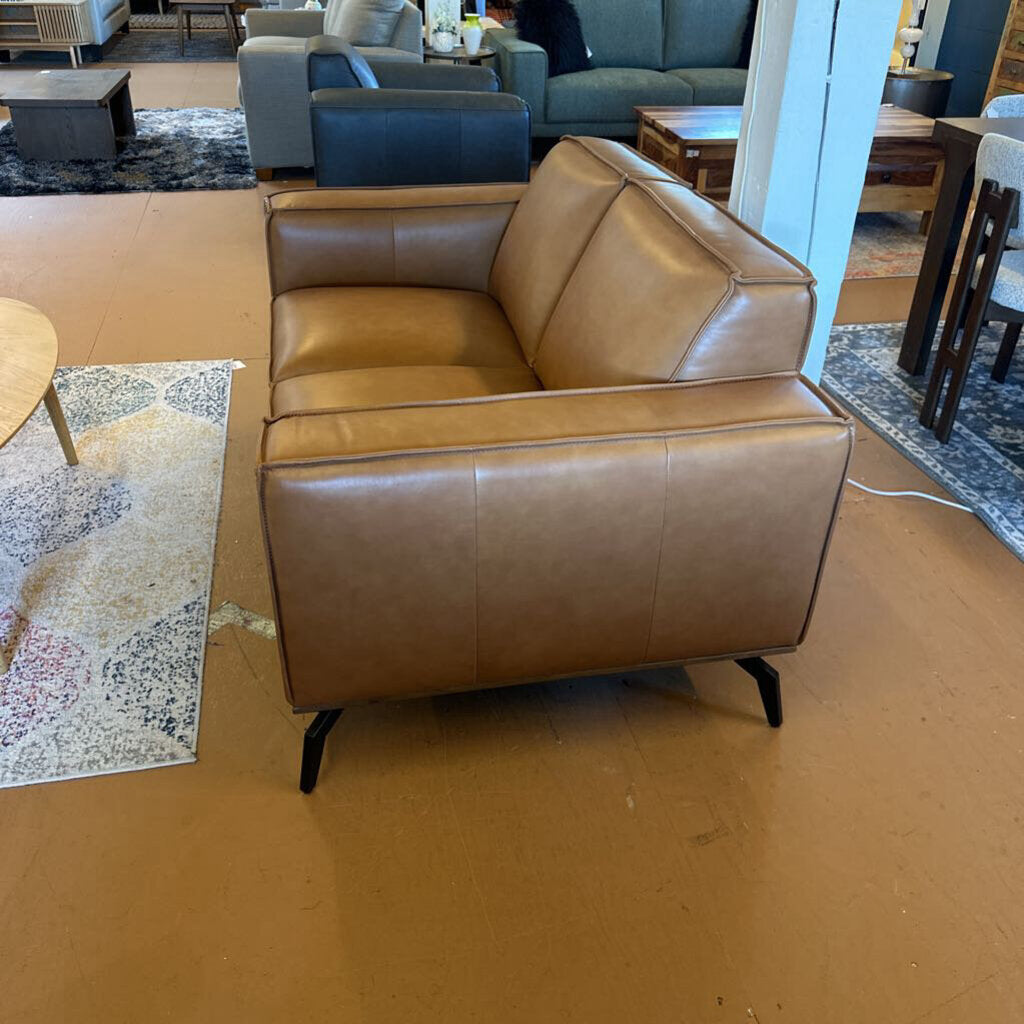 Brown leather sofa in a room with patterned rug and furniture.